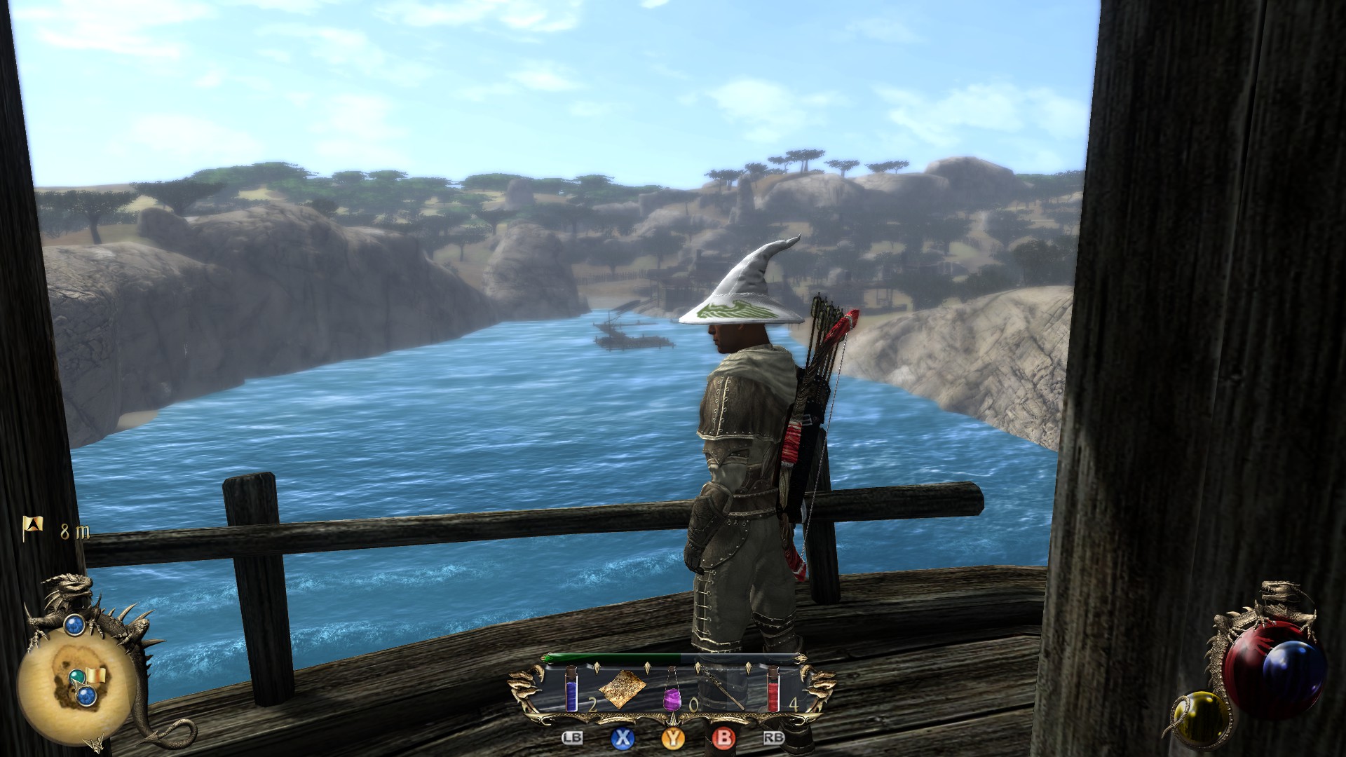 A man wearing a silly robe and wizard hat poses on a bridge over a wide river. The shores on either side are dusty with a savannah in the distance.